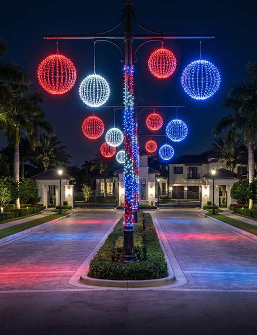 Red, white, and blue illuminated light spheres at a community entrance at night